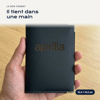 Porte-carte grise Aprilia en simili cuir tenu dans une main