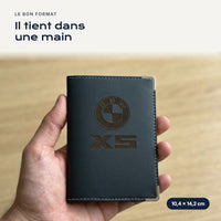 Porte-carte grise BMW X5 en simili cuir tenu dans une main