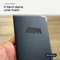 Porte-carte grise Pack M en simili cuir tenu dans une main