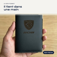 Porte-carte grise Peugeot 208 en simili cuir tenu dans une main