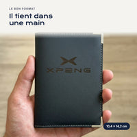 Porte-carte grise Xpeng en simili cuir tenu dans une main