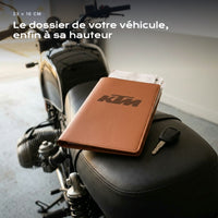 Porte-documents KTM posé sur un siège, avec des factures